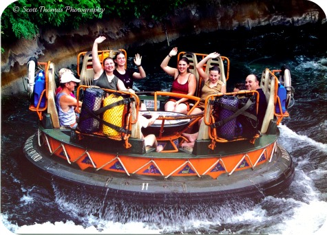Soaked riders wave to the photographer towards the end of the Kali River Rapids in Disney's Animal Kingdom, Walt Disney World, Orlando, Florida