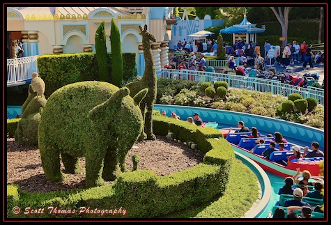Elephant and giraffe topiaries watch over It's a Small World boats filled with guests pass by at Disneyland, Anaheim, California